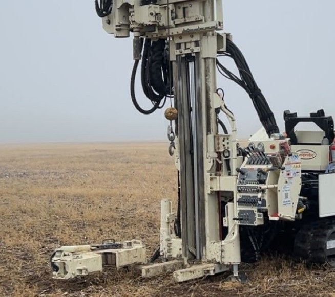 Oil drilling rig on a flat, barren field under a gray sky
