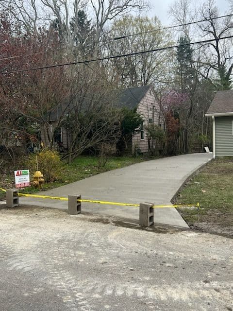New concrete driveway blocked by cinder blocks and yellow tape.