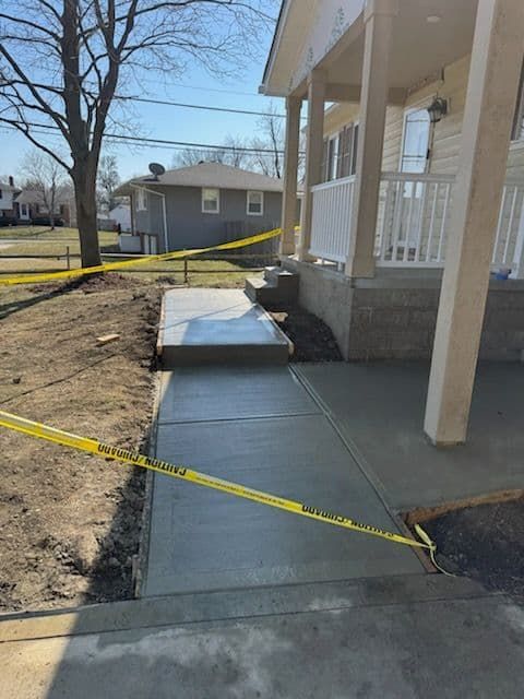 New concrete sidewalk leading to a house porch, with caution tape.