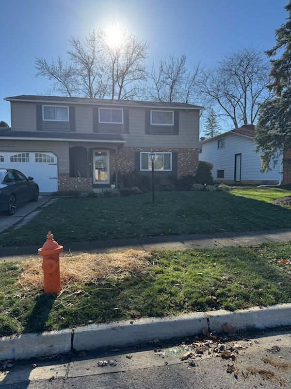 Two-story house with green lawn, fire hydrant, sunny day.