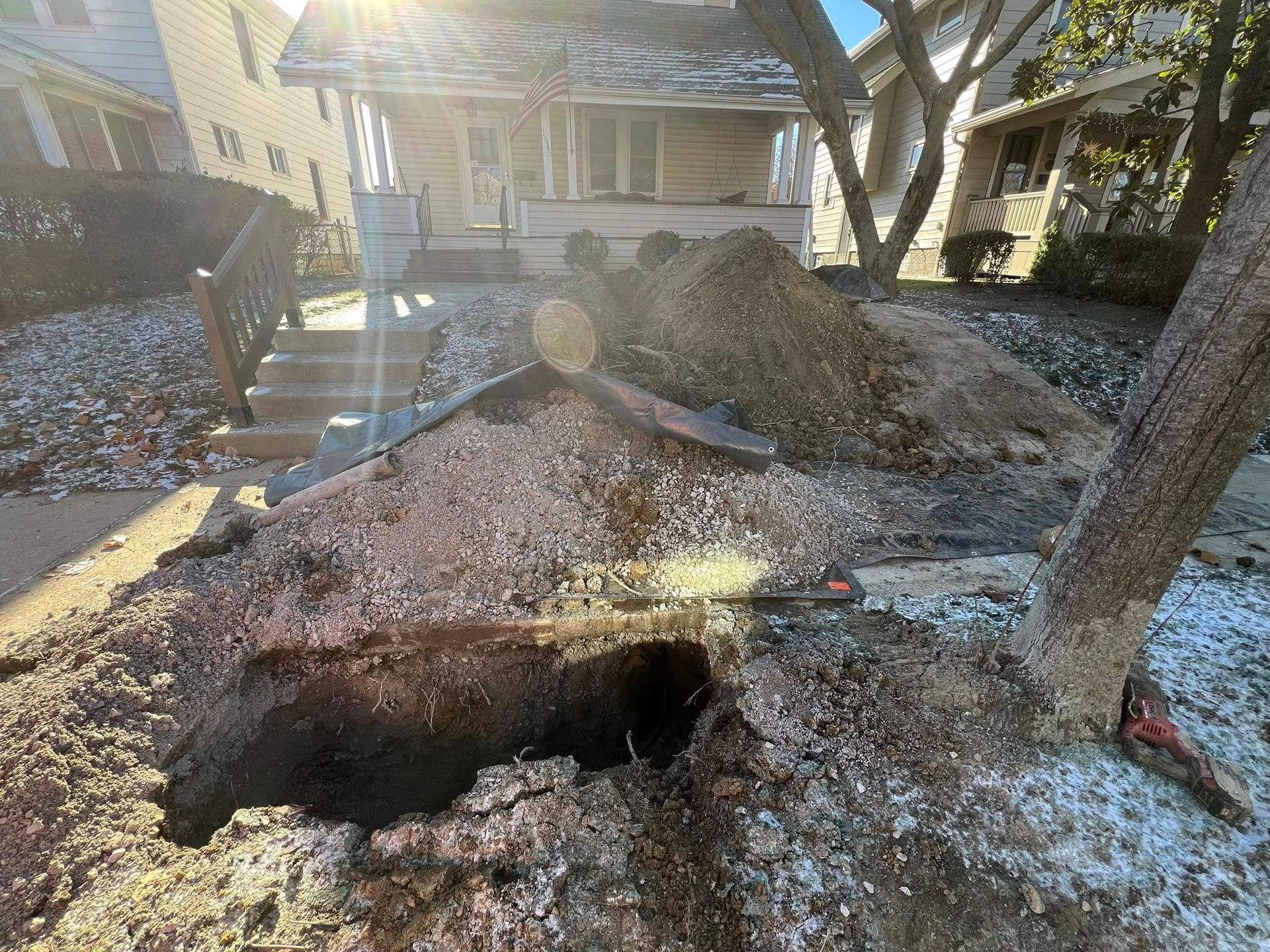 Eroded front yard exposing tree roots, large hole, house in background.