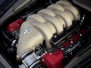 Close-up of a Maserati engine with a beige intake manifold and red valve covers.