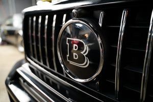 Close-up of a black car grille with a chrome “B” emblem.
