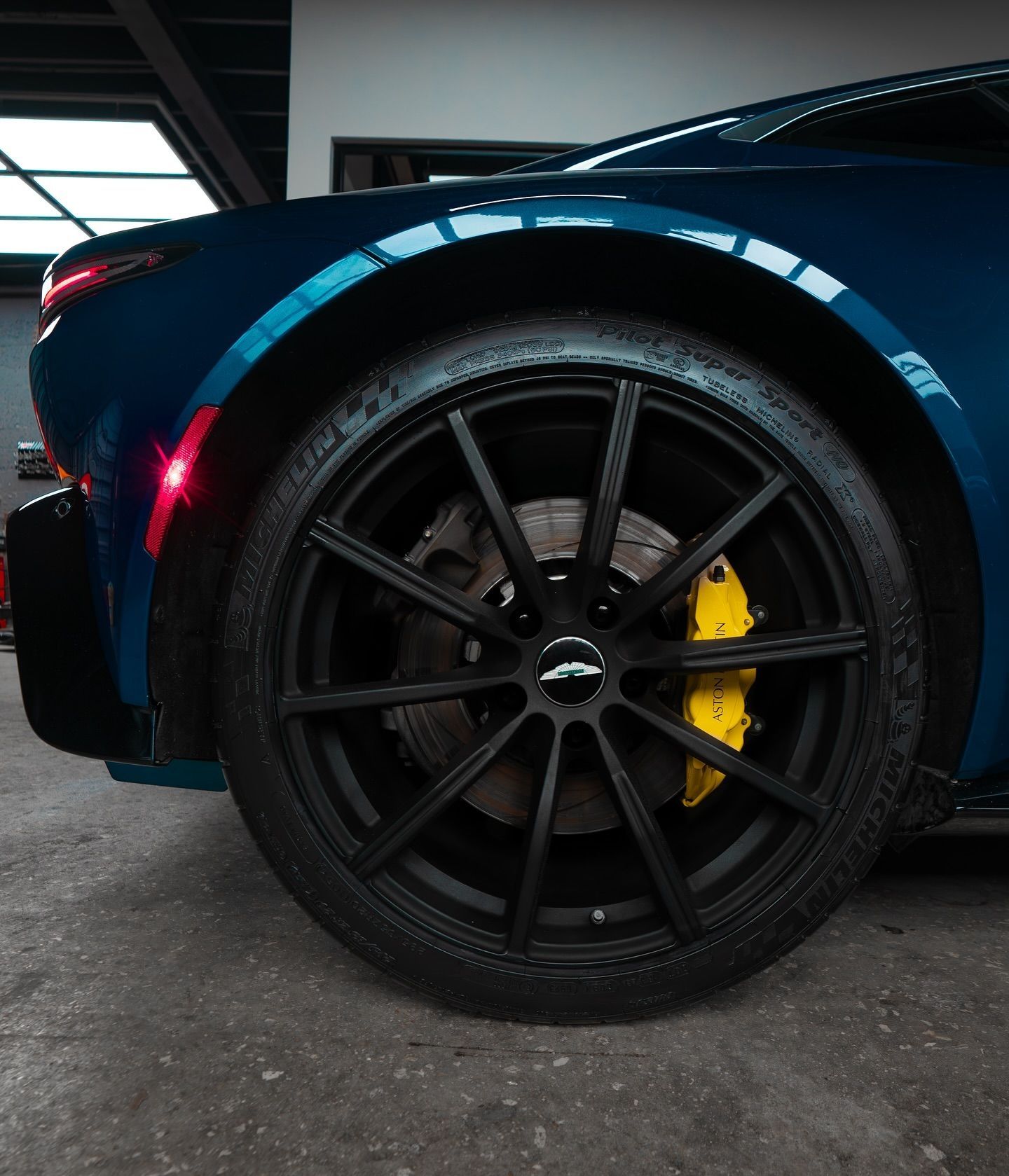 Blue sports car with black rim and yellow brake caliper.