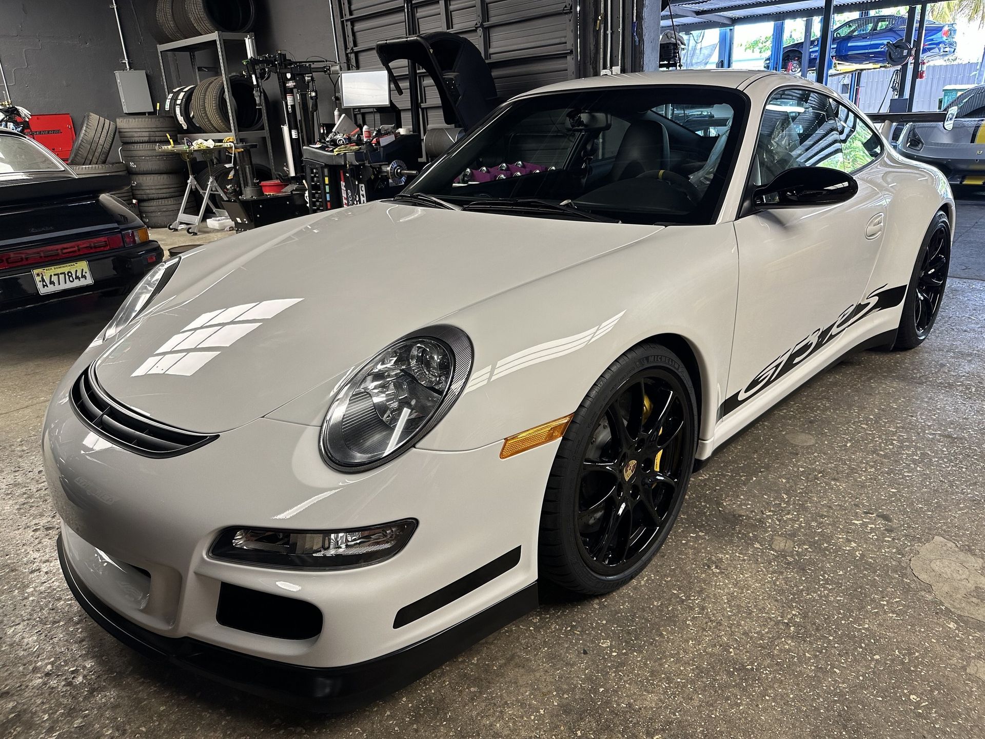 White Porsche sports car with black accents parked in a garage.
