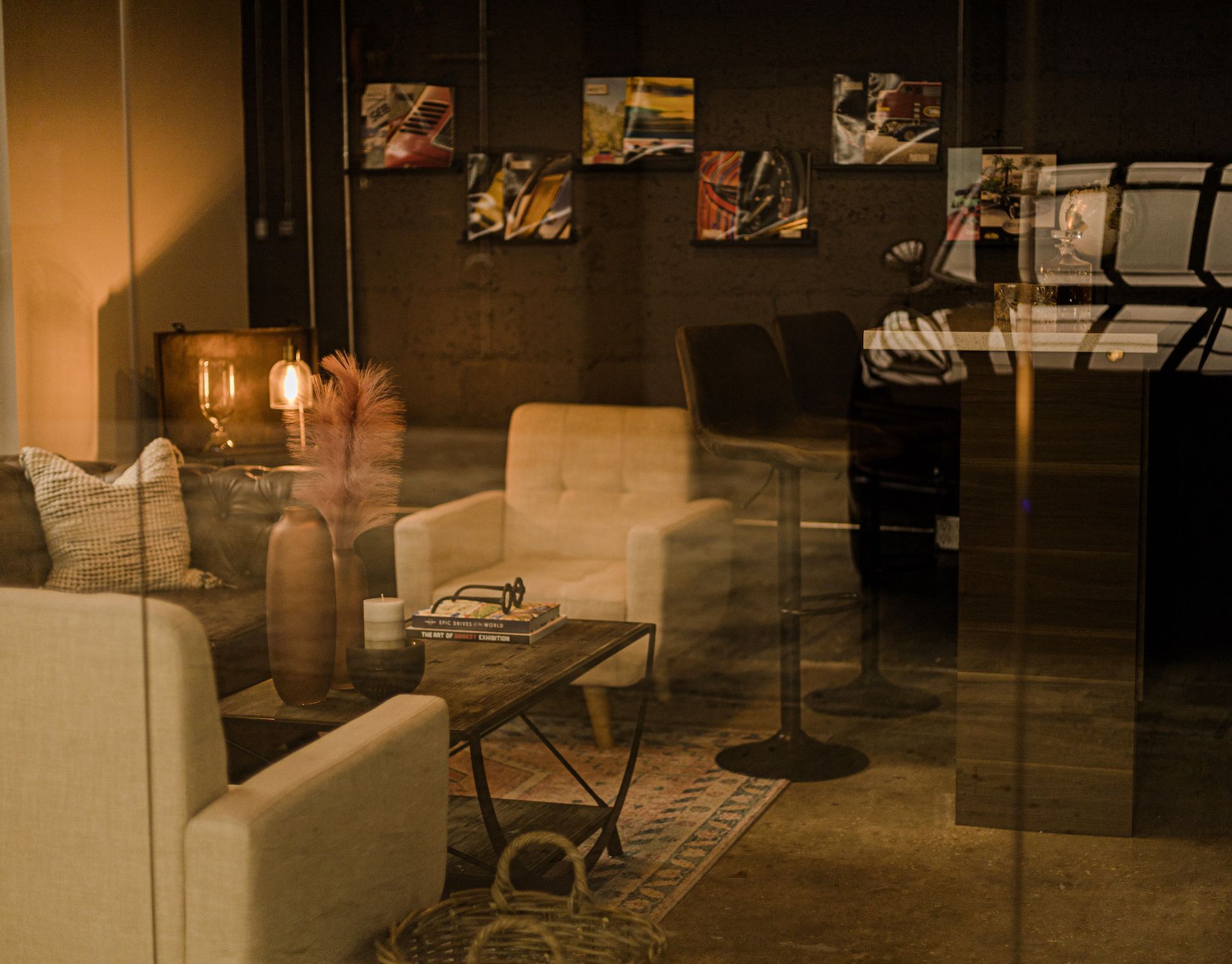 Cozy lounge area with cream armchairs, coffee table, art on the wall, and glass door reflection.