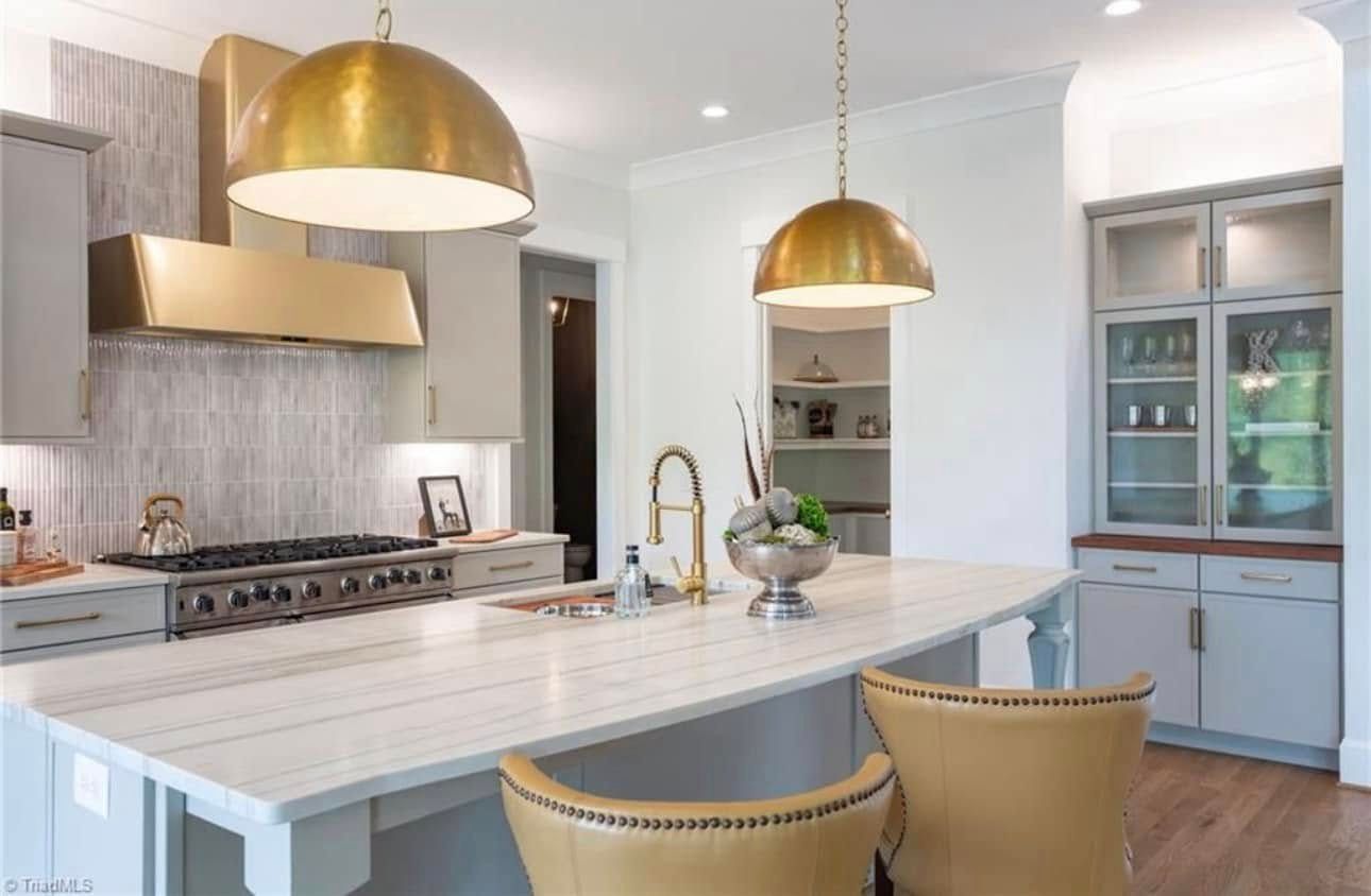 A kitchen with a large island and two chairs.