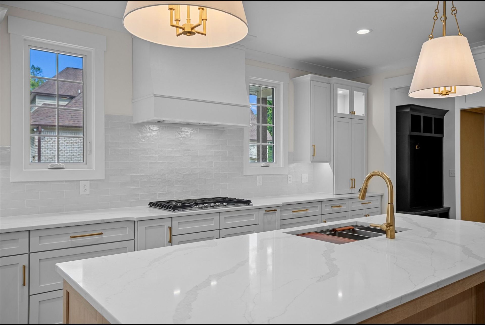 A kitchen with white cabinets, white counter tops, a sink, and a stove.