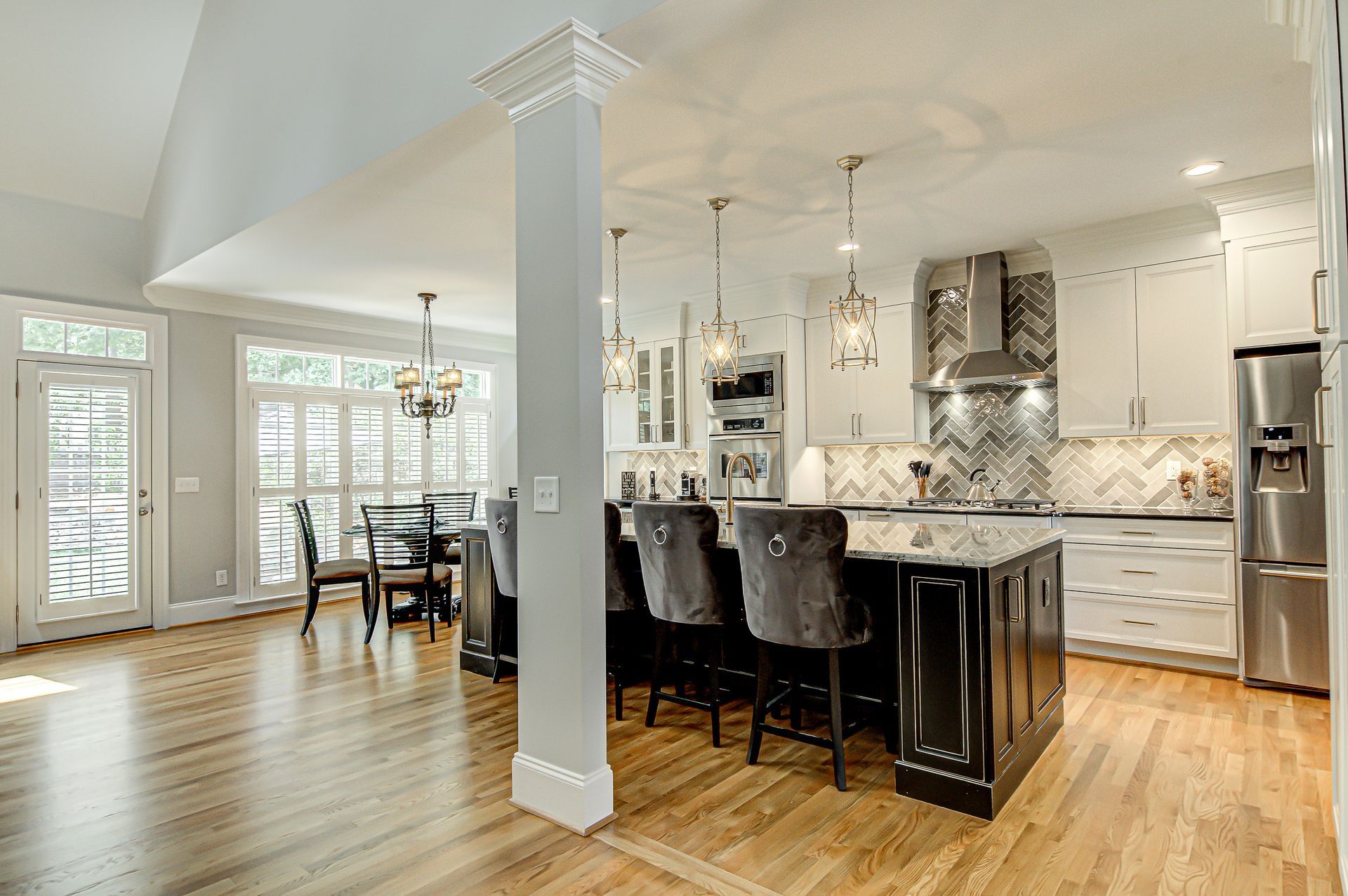 A kitchen with a large island, stainless steel appliances, white cabinets, and hardwood floors.