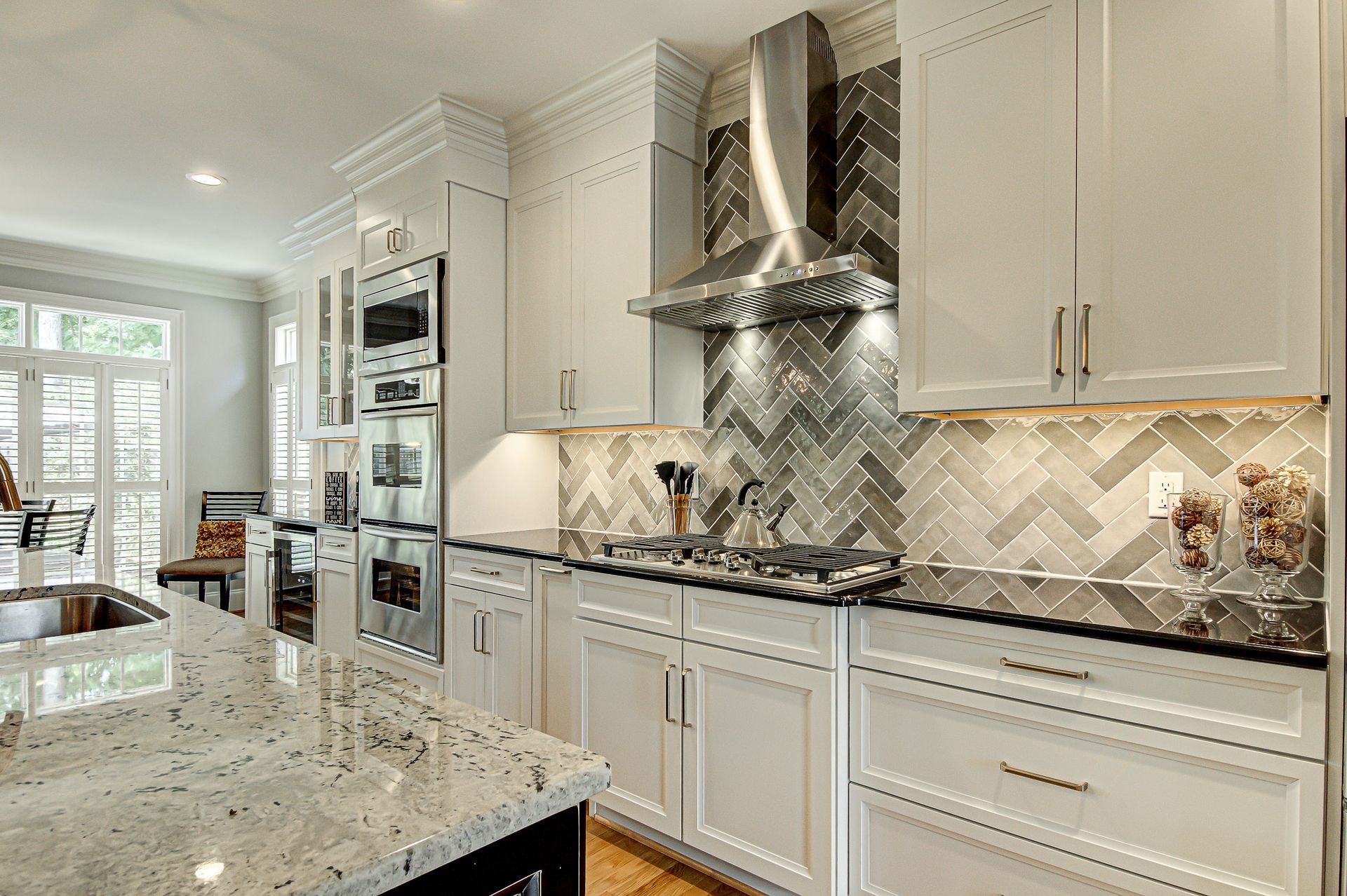 A kitchen with white cabinets, granite counter tops, and stainless steel appliances.