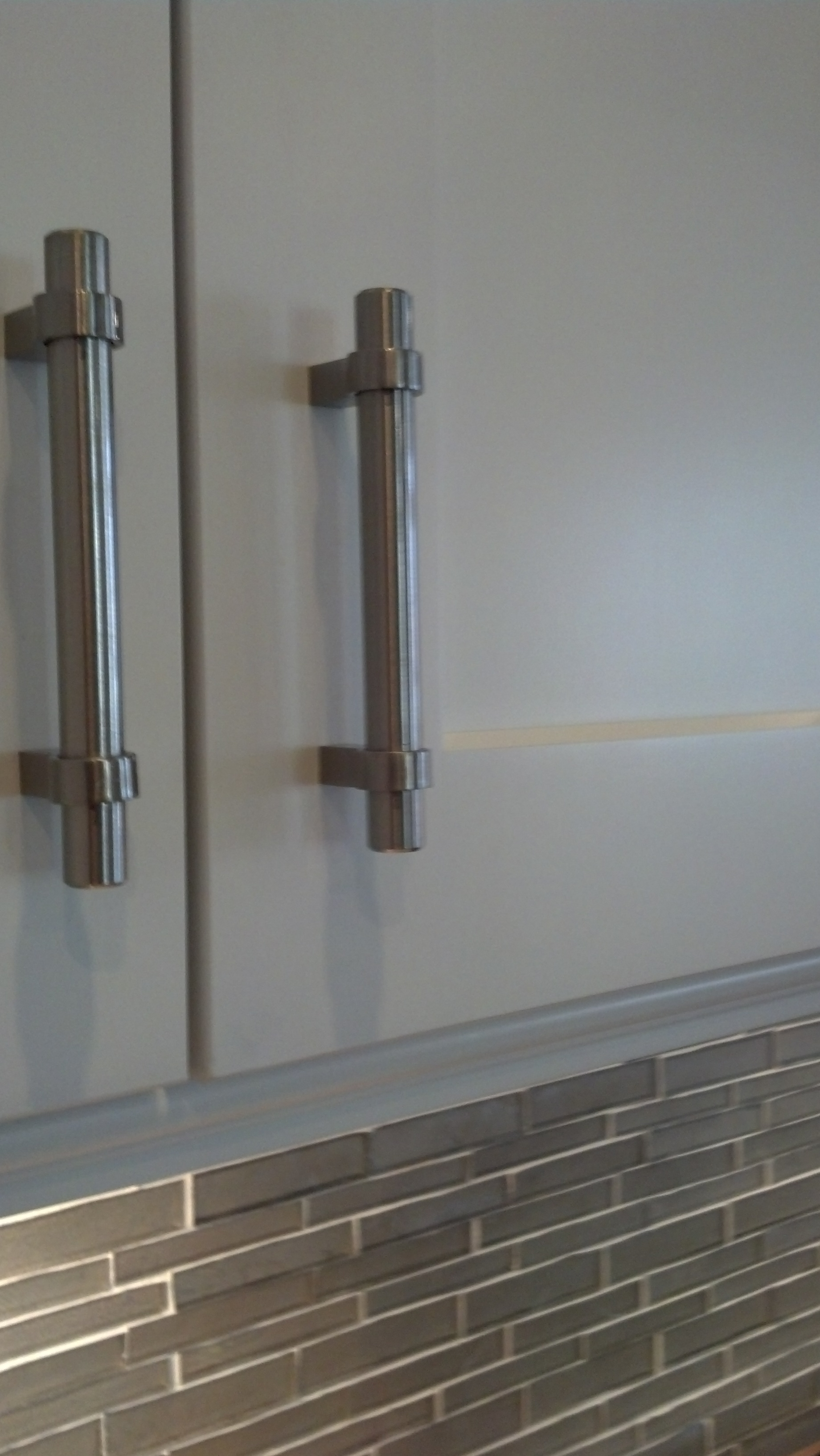 A close up of a kitchen cabinet with stainless steel handles.