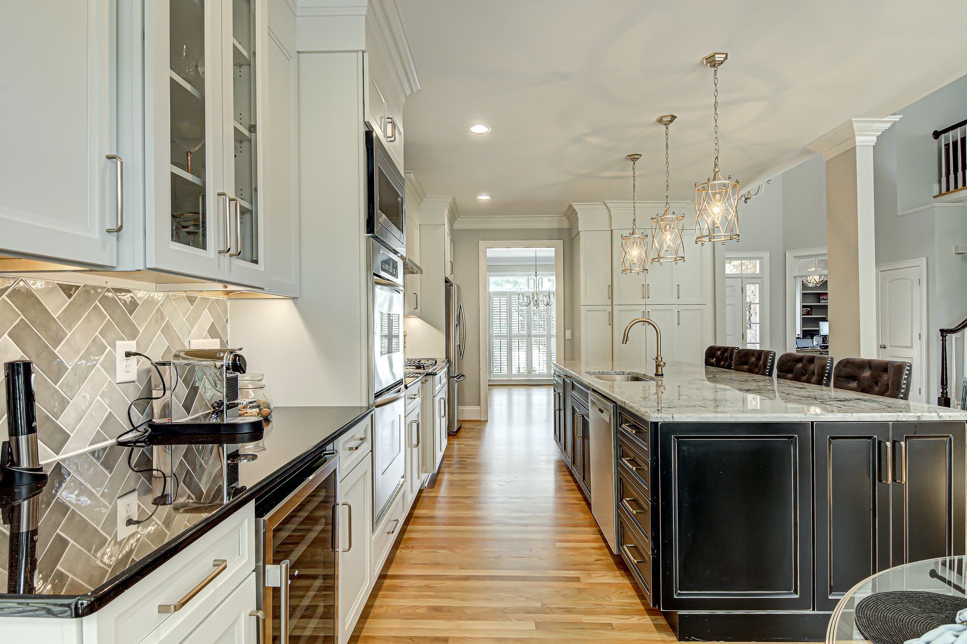 A kitchen with white cabinets, black counter tops, and stainless steel appliances.