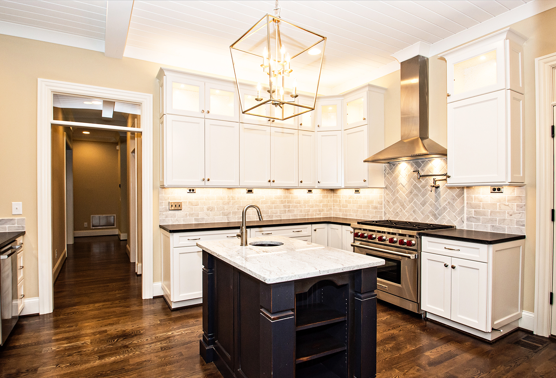 A kitchen with white cabinets , stainless steel appliances , and a large island.