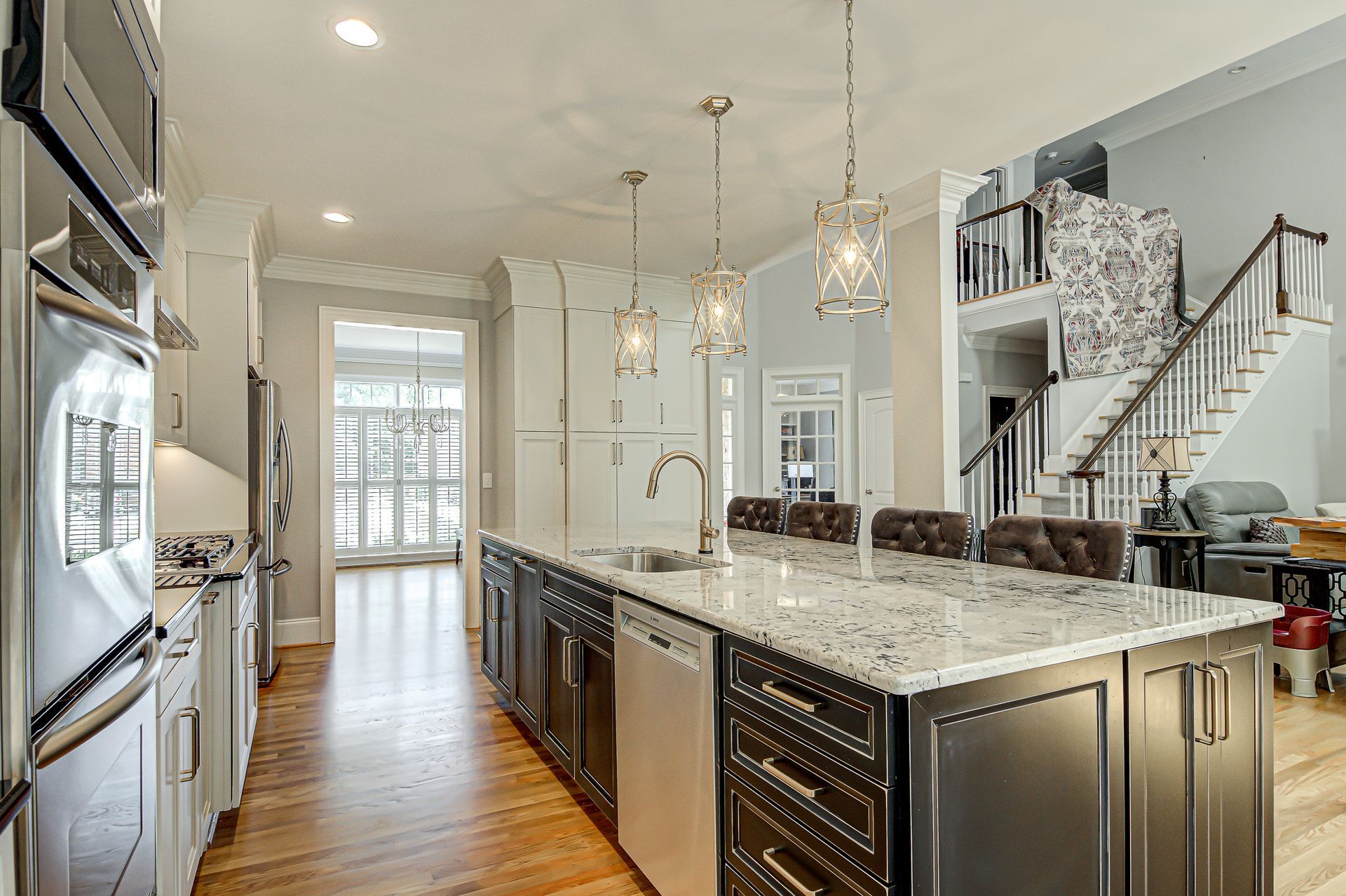 A kitchen with stainless steel appliances, granite counter tops, and a large island.