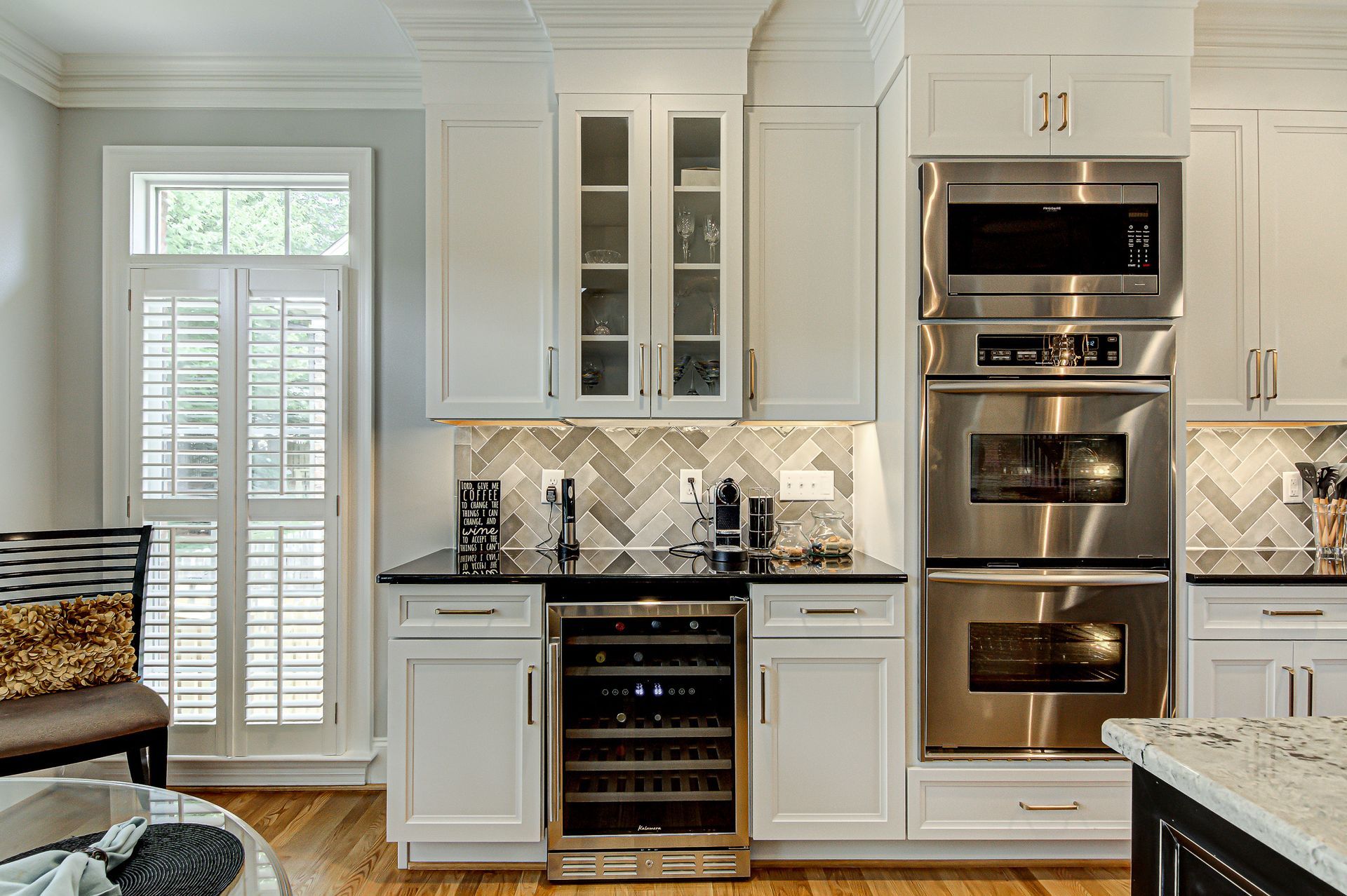 A kitchen with white cabinets, stainless steel appliances, a wine cooler, and a microwave.