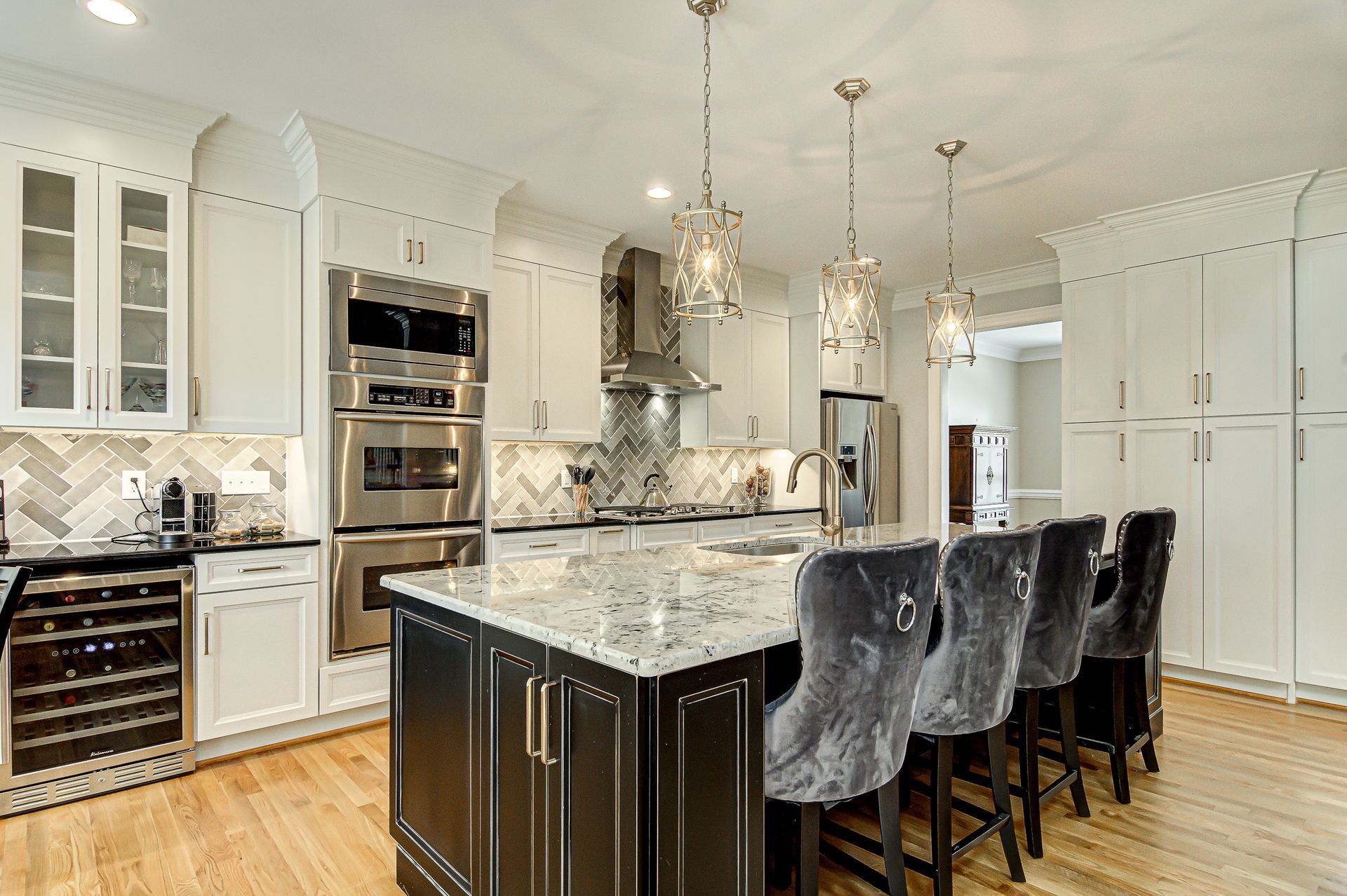 A kitchen with white cabinets, stainless steel appliances, granite counter tops, and a large island.