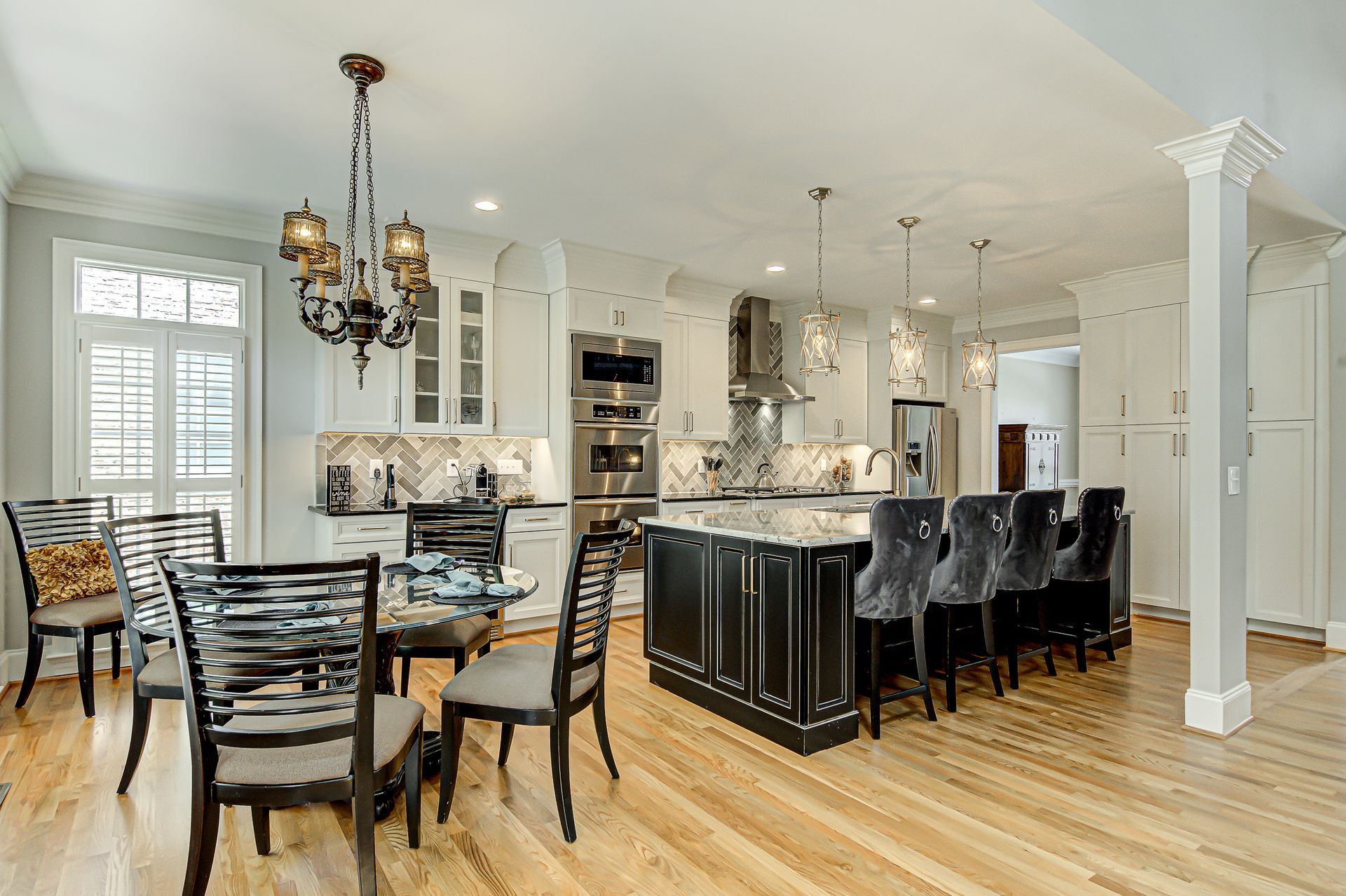 A kitchen and dining room in a house with hardwood floors and white cabinets.