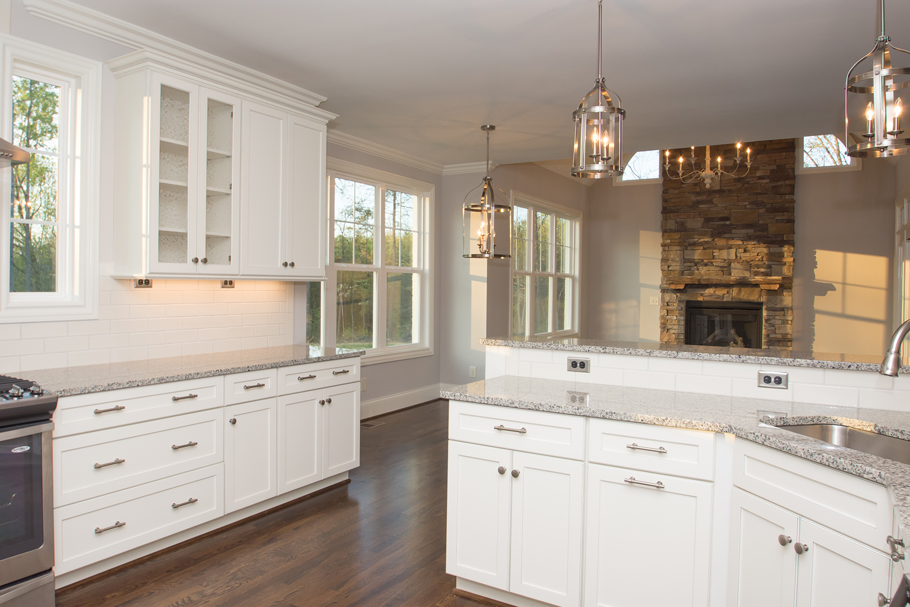A kitchen with white cabinets , granite counter tops , stainless steel appliances and a fireplace.