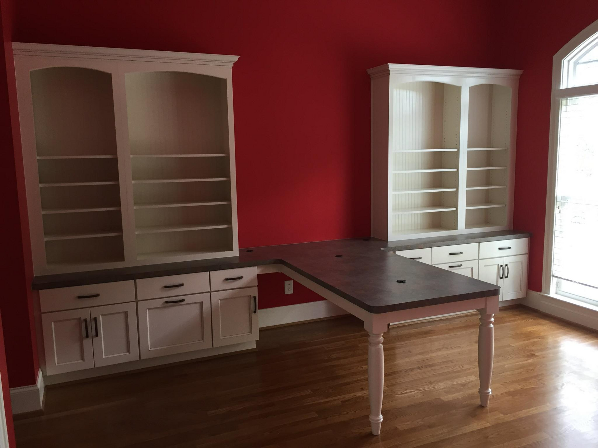 An empty room with red walls and white cabinets and shelves.
