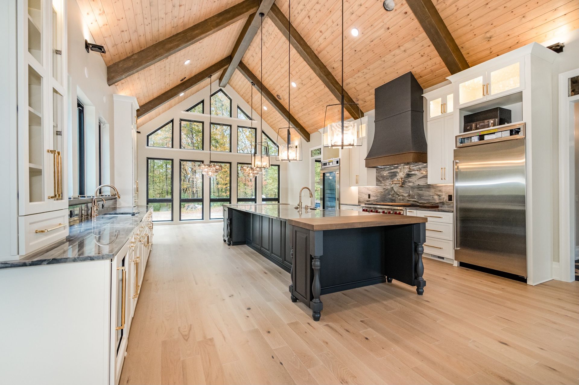 Spacious modern kitchen with vaulted wood ceiling, large island, and stainless steel appliances.