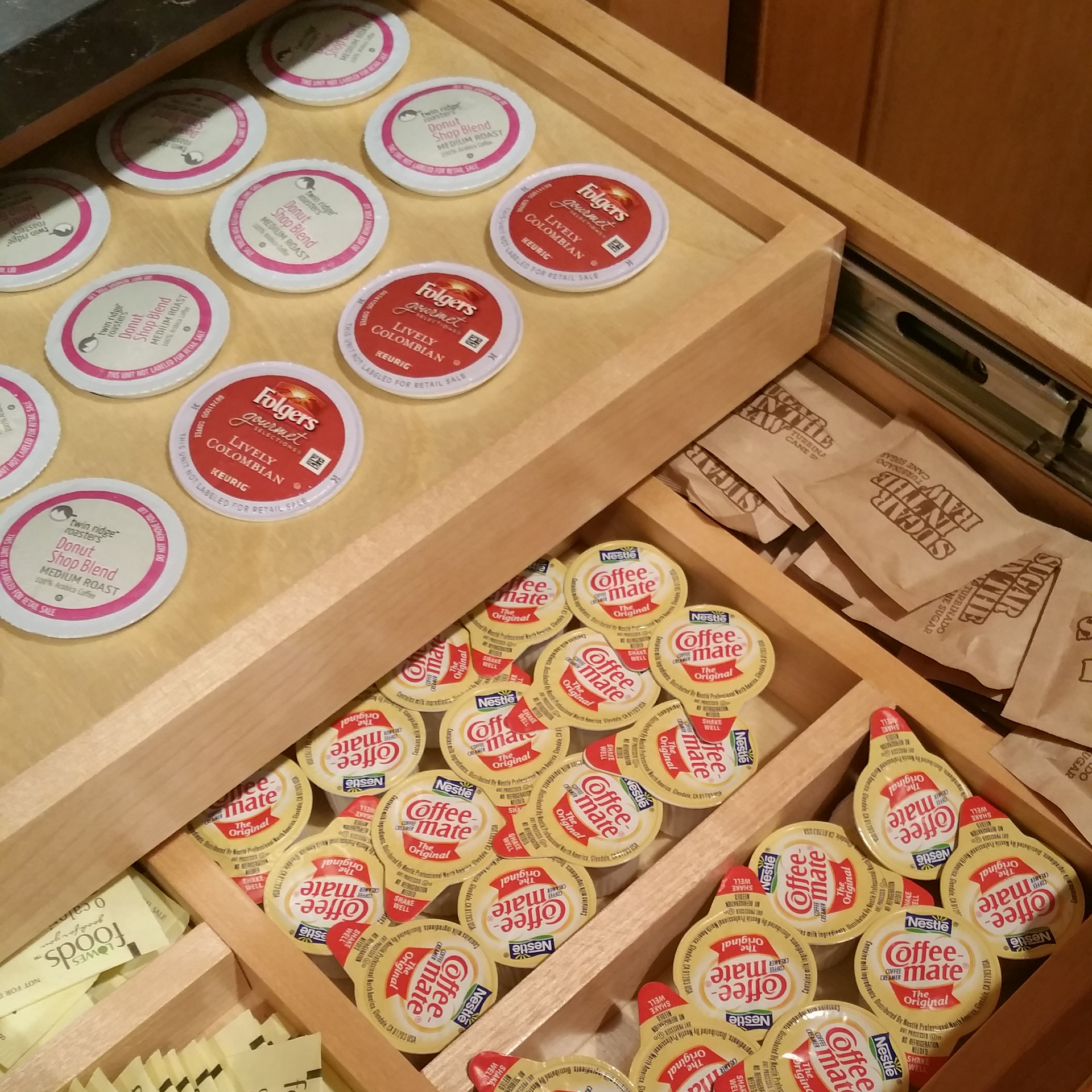 A wooden drawer filled with coffee creamer