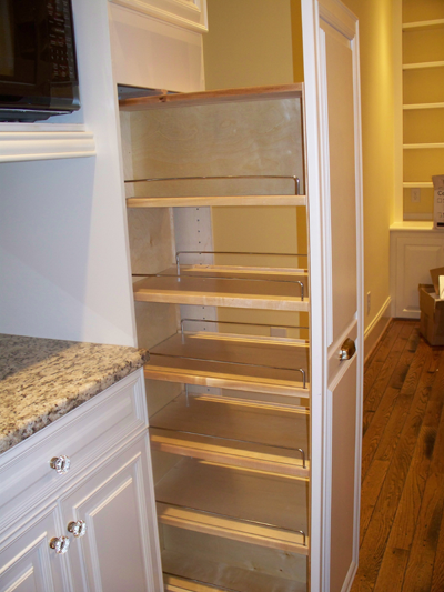 A pantry in a kitchen with a microwave on top of it.