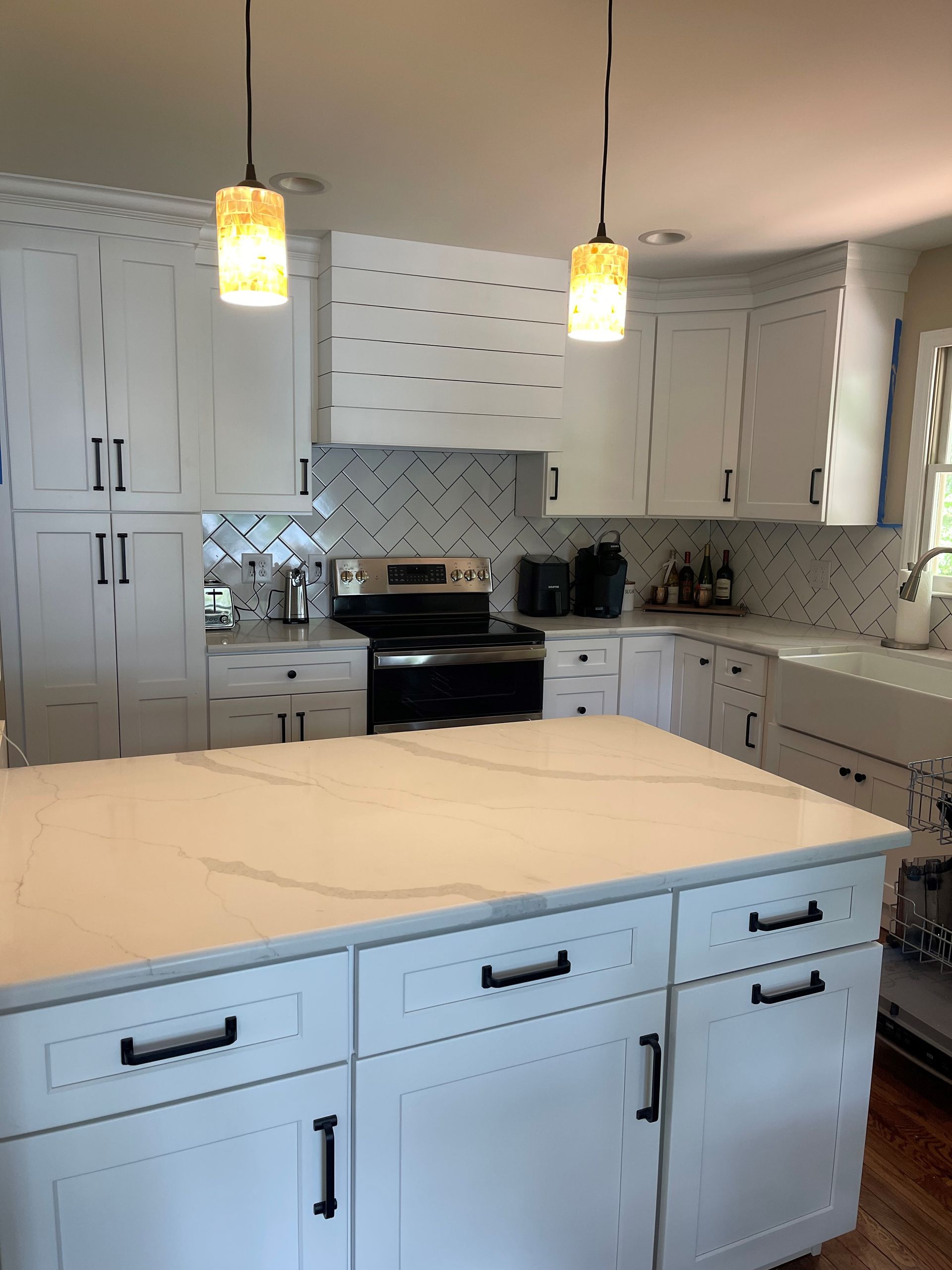 A kitchen with white cabinets and a large island in the middle.