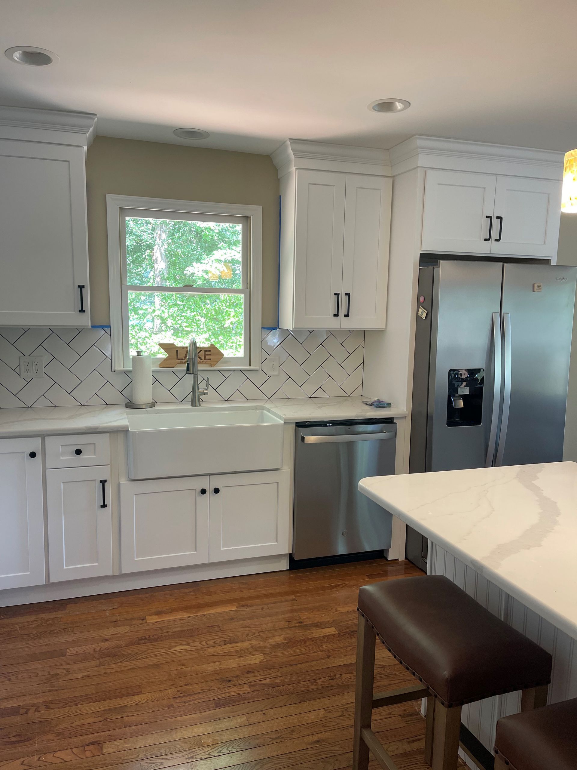 A kitchen with white cabinets and a stainless steel refrigerator