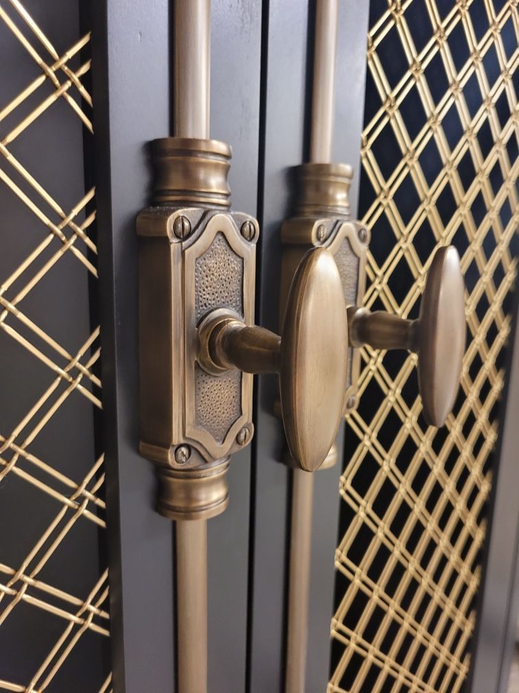 A close up of a brass door handle on a black and gold door.