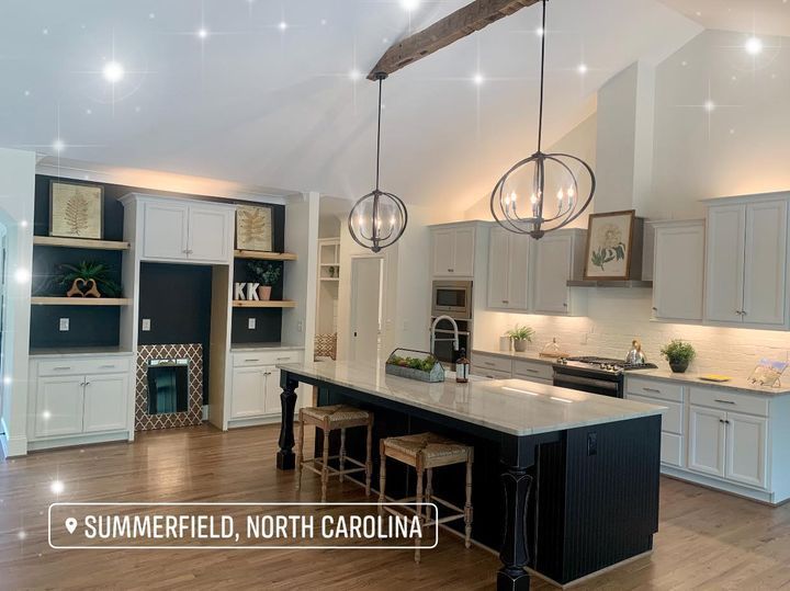 A kitchen with white cabinets and a large island in summerfield , north carolina.