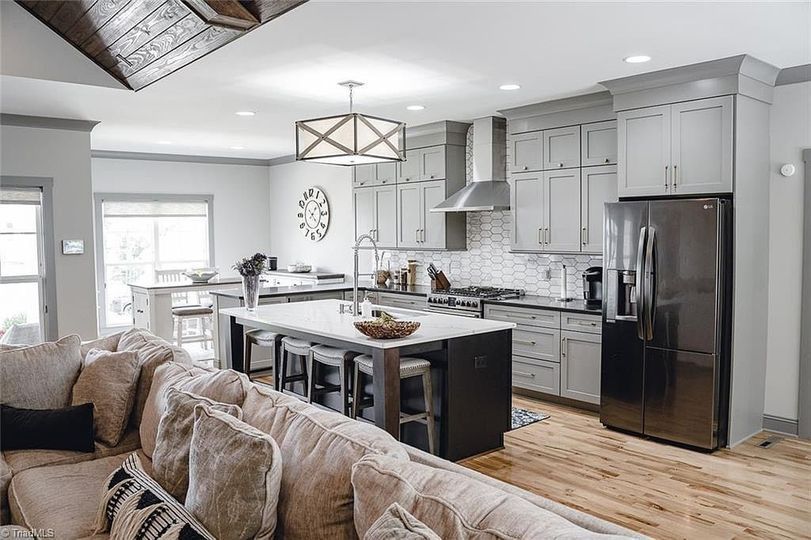 A living room filled with furniture and a kitchen with stainless steel appliances.
