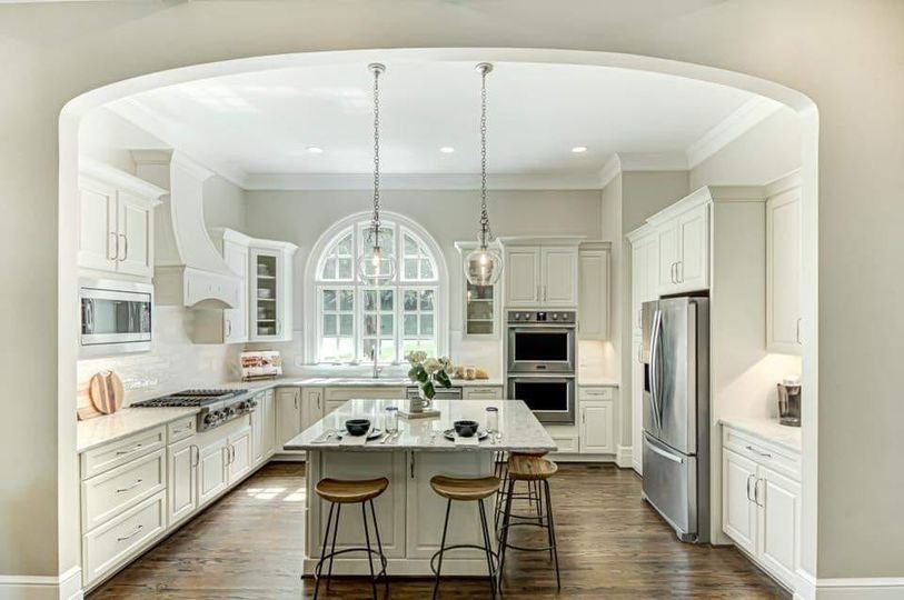 A kitchen with white cabinets , stainless steel appliances , and a large island.