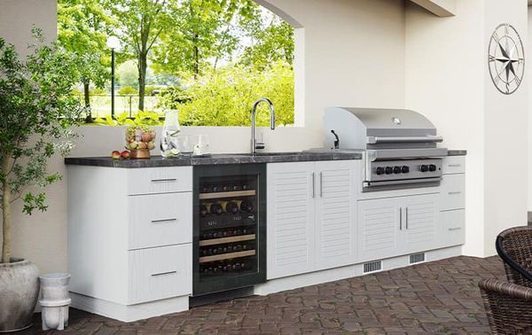 A kitchen with a grill , sink , and wine cooler.