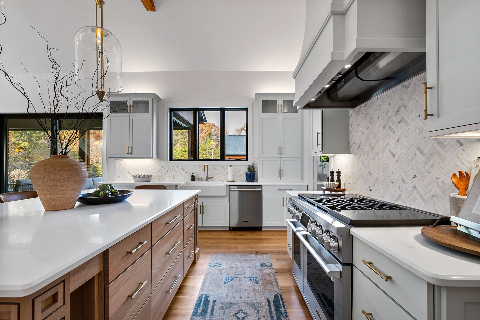 Modern kitchen with white cabinets, wooden island, stainless steel appliances, and a patterned backsplash.