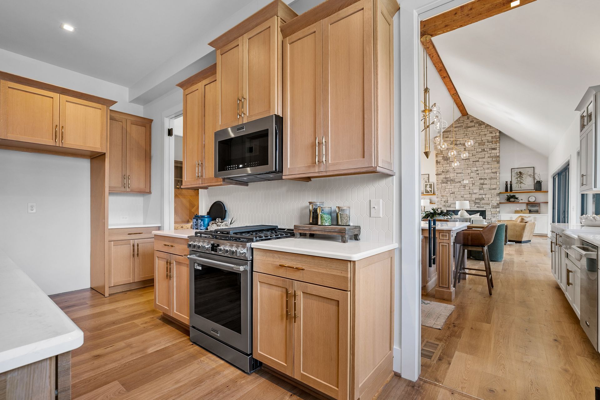 Kitchen with light wood cabinets, stainless steel appliances, and view into living area.