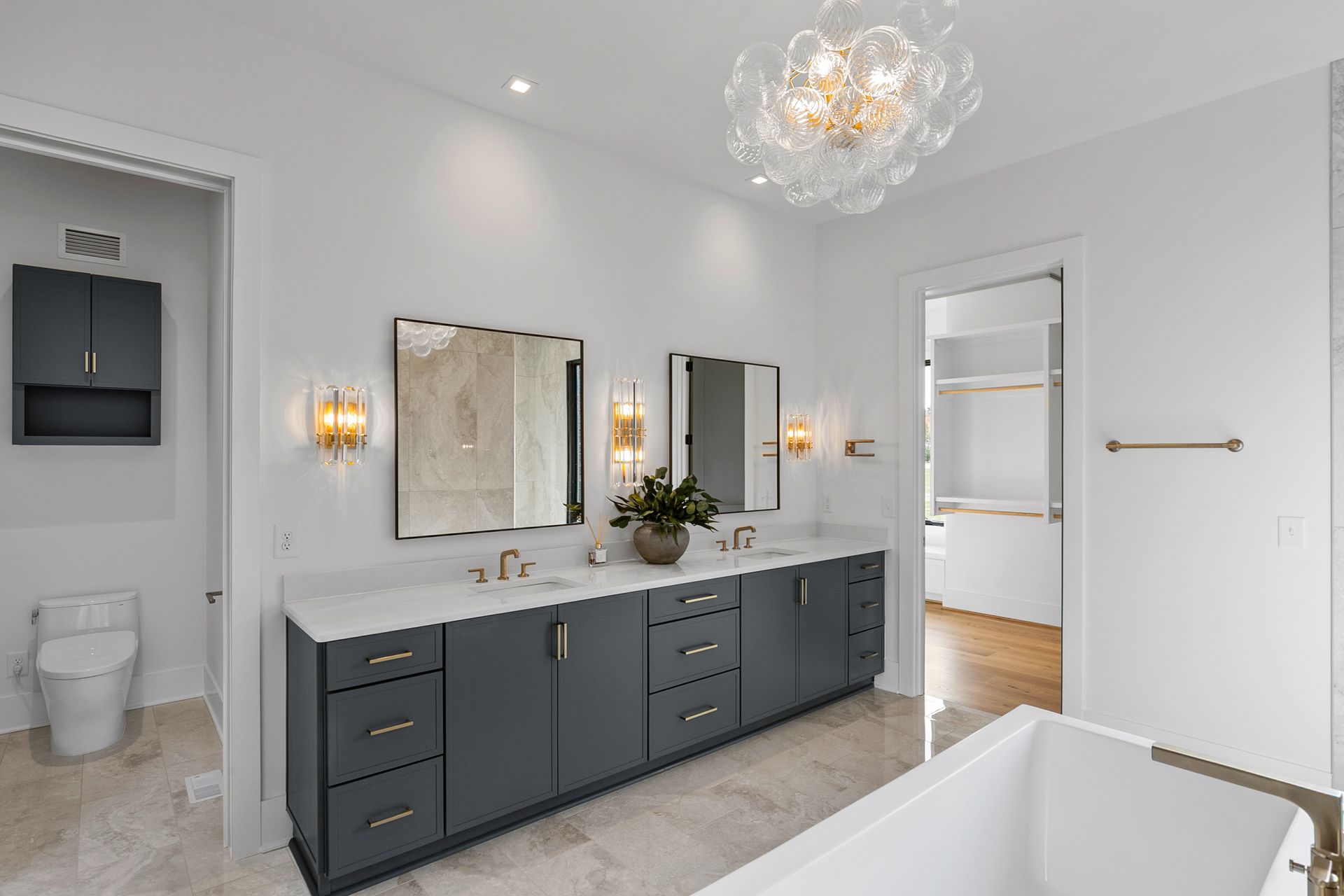 Modern bathroom with gray vanity, double mirrors, and a decorative light fixture.