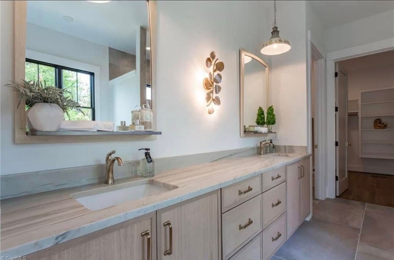 A bathroom with two sinks , two mirrors , and a large vanity.
