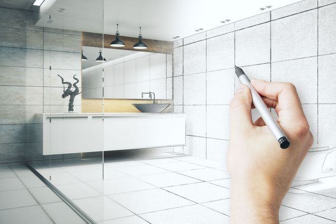 Hand drawing a bathroom renovation sketch on a tiled wall layout with modern fixtures.