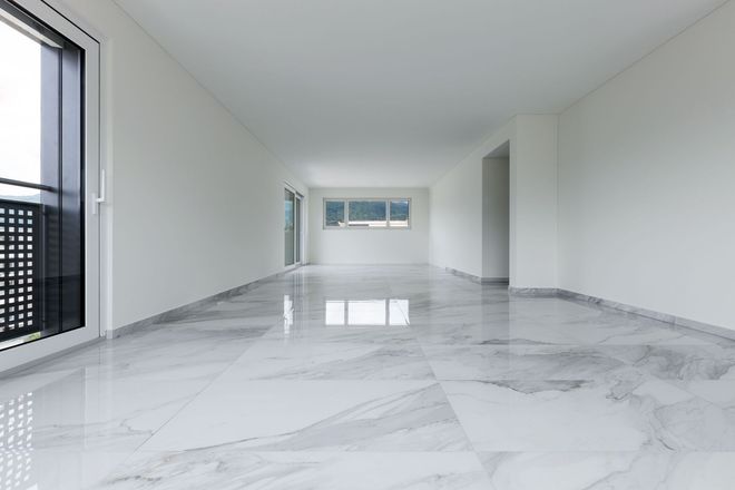 Empty modern room with glossy white marble floor, large windows, and minimalist white walls.