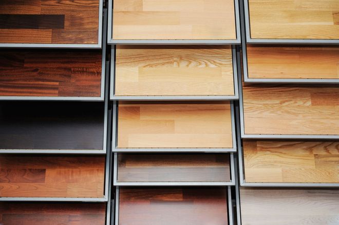 Stacked wooden flooring samples in a display rack, showing different wood tones and textures.