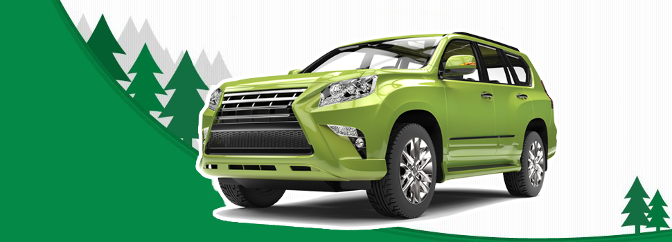 A green SUV is parked on the side of a mountain with trees in the background.