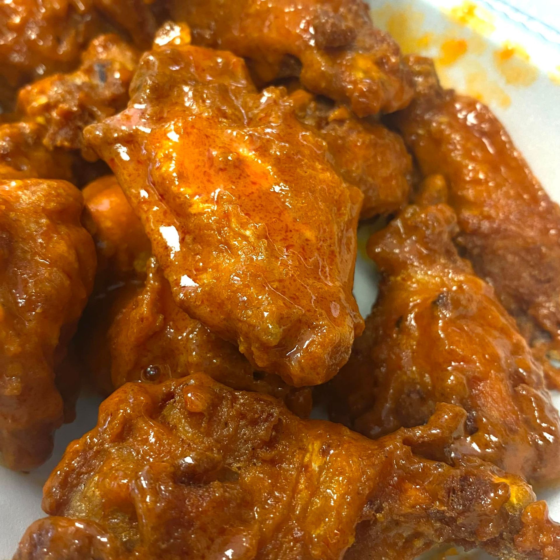 A close up of a plate of buffalo chicken wings on a table.