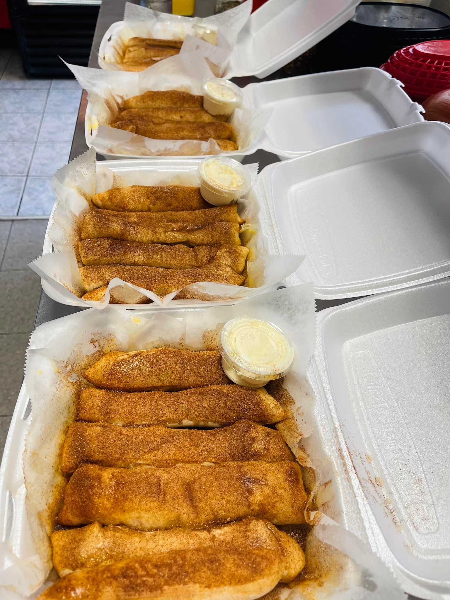 A row of styrofoam containers filled with food on a table.