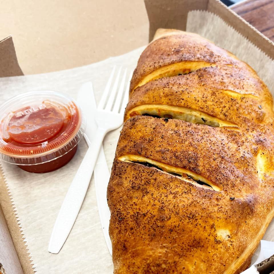 A close up of a calzone next to a fork and ketchup