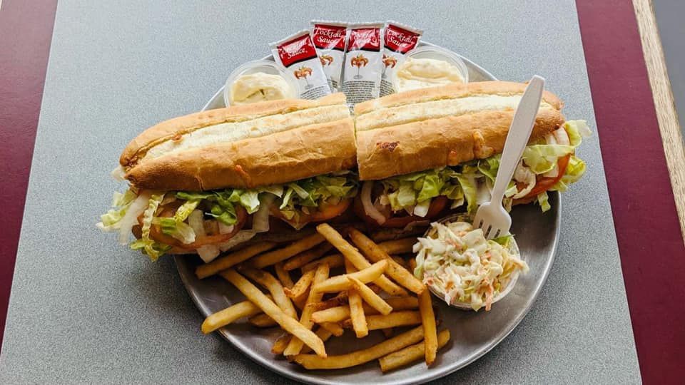 A sandwich and french fries on a plate on a table.