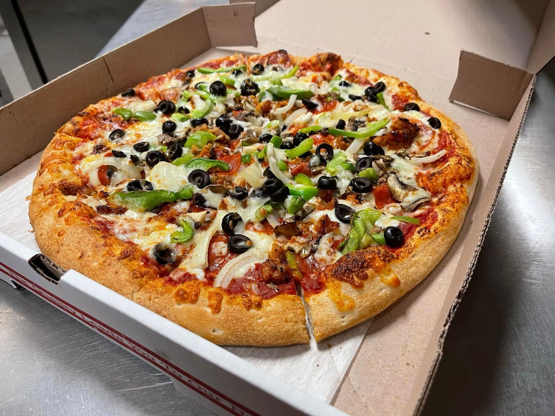 A pizza is sitting in a cardboard box on a table.