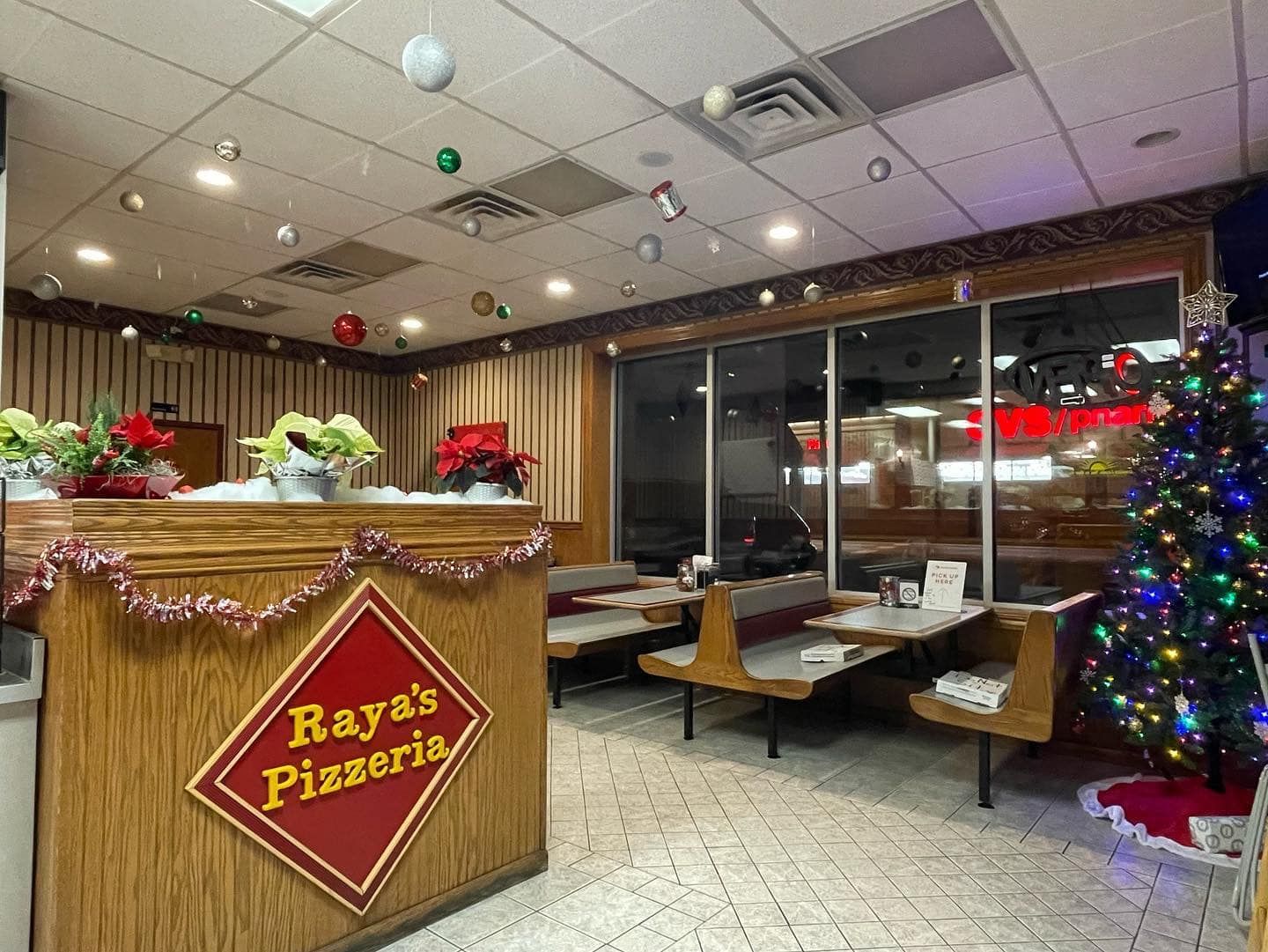 The inside of a restaurant decorated for christmas with a christmas tree.