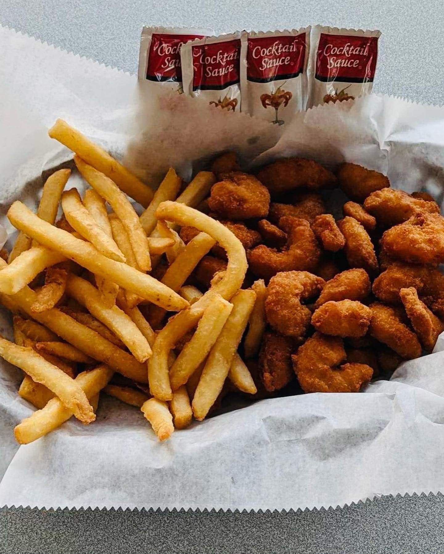 A basket filled with french fries and fried shrimp