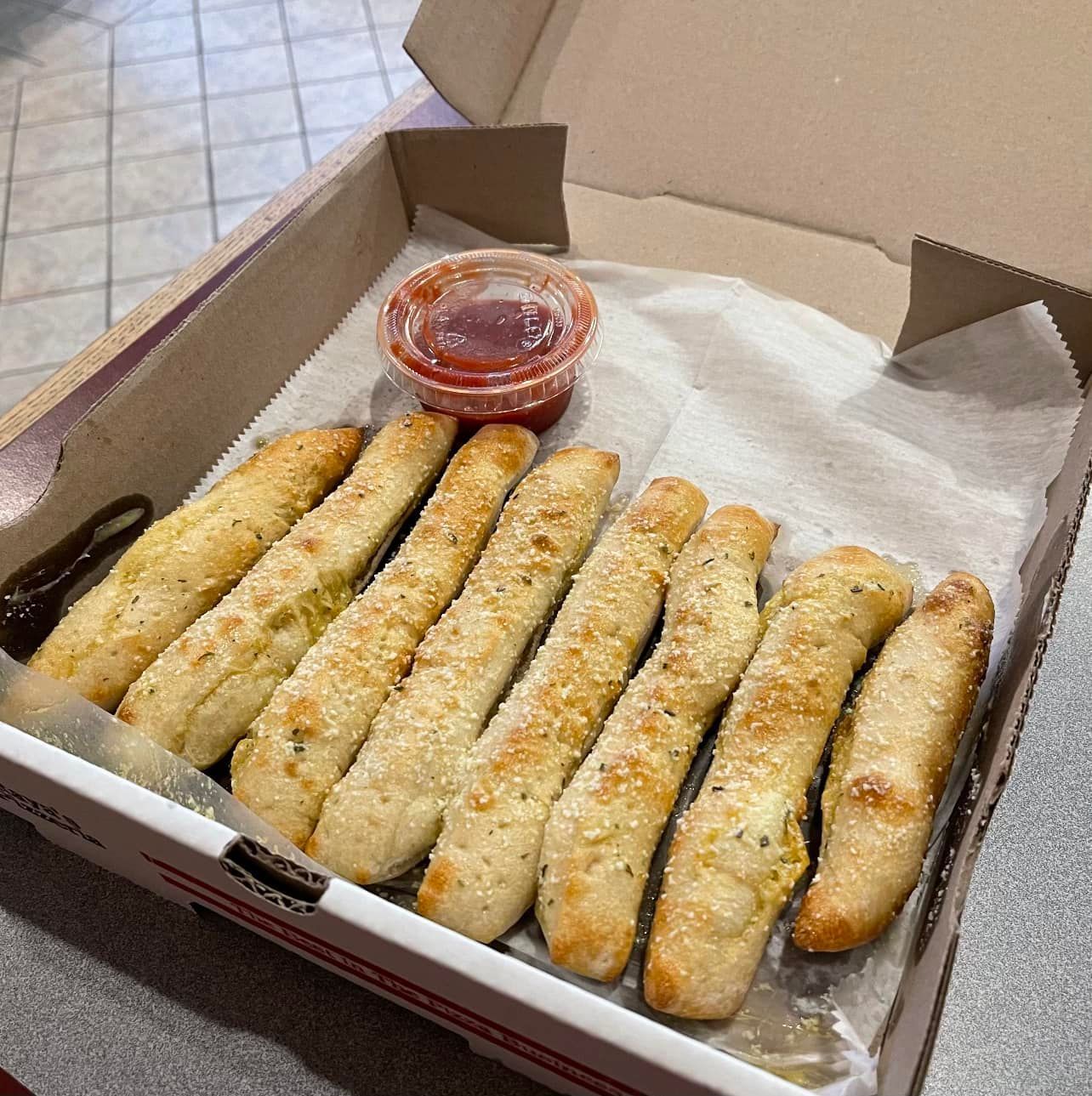 A box of garlic sticks with a dipping sauce
