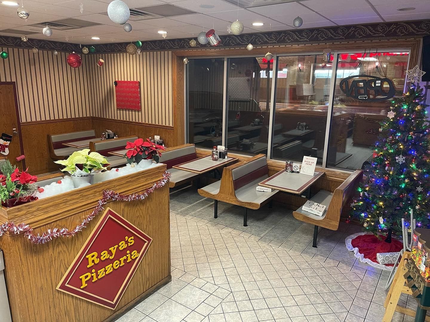 The inside of a restaurant decorated for christmas with tables and benches and a christmas tree.